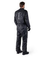 Tuta Alpinestars Hurricane Rain V2, tuta da moto antipioggia monopezzo impermeabile, nera, vista posteriore con grande logo riflettente verticale, tessuto leggero e resistente al vento, indossata con guanti e stivali neri