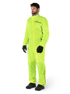 Alpinestars Hurricane Rain V2 Suit, tuta da moto impermeabile monopezzo, Giallo Fluo, indossata con guanti e stivali neri, con logo Alpinestars nero sul petto e dettagli riflettenti sulle gambe