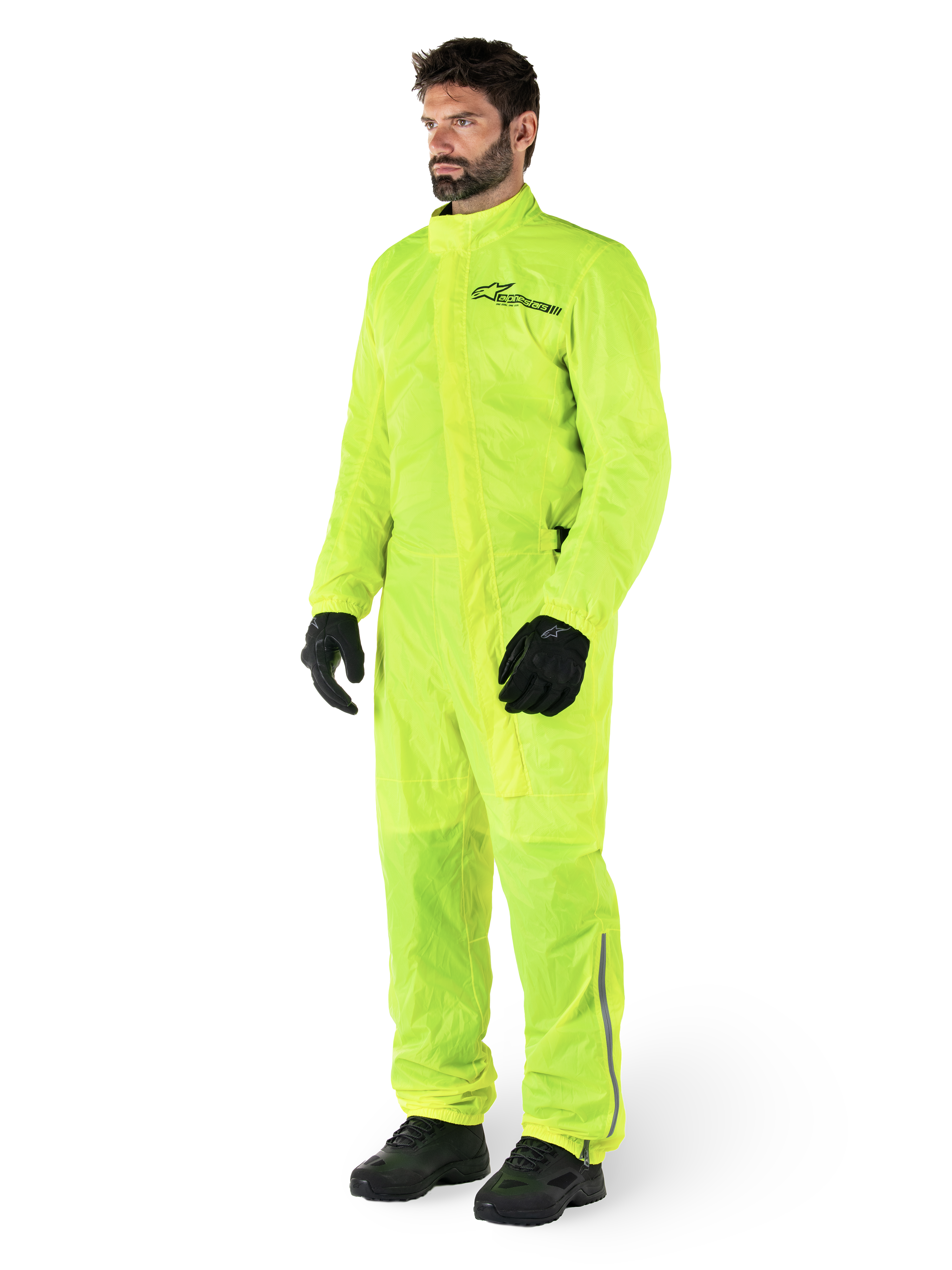 Alpinestars Hurricane Rain V2 Suit, tuta da moto impermeabile monopezzo, Giallo Fluo, indossata con guanti e stivali neri, con logo Alpinestars nero sul petto e dettagli riflettenti sulle gambe
