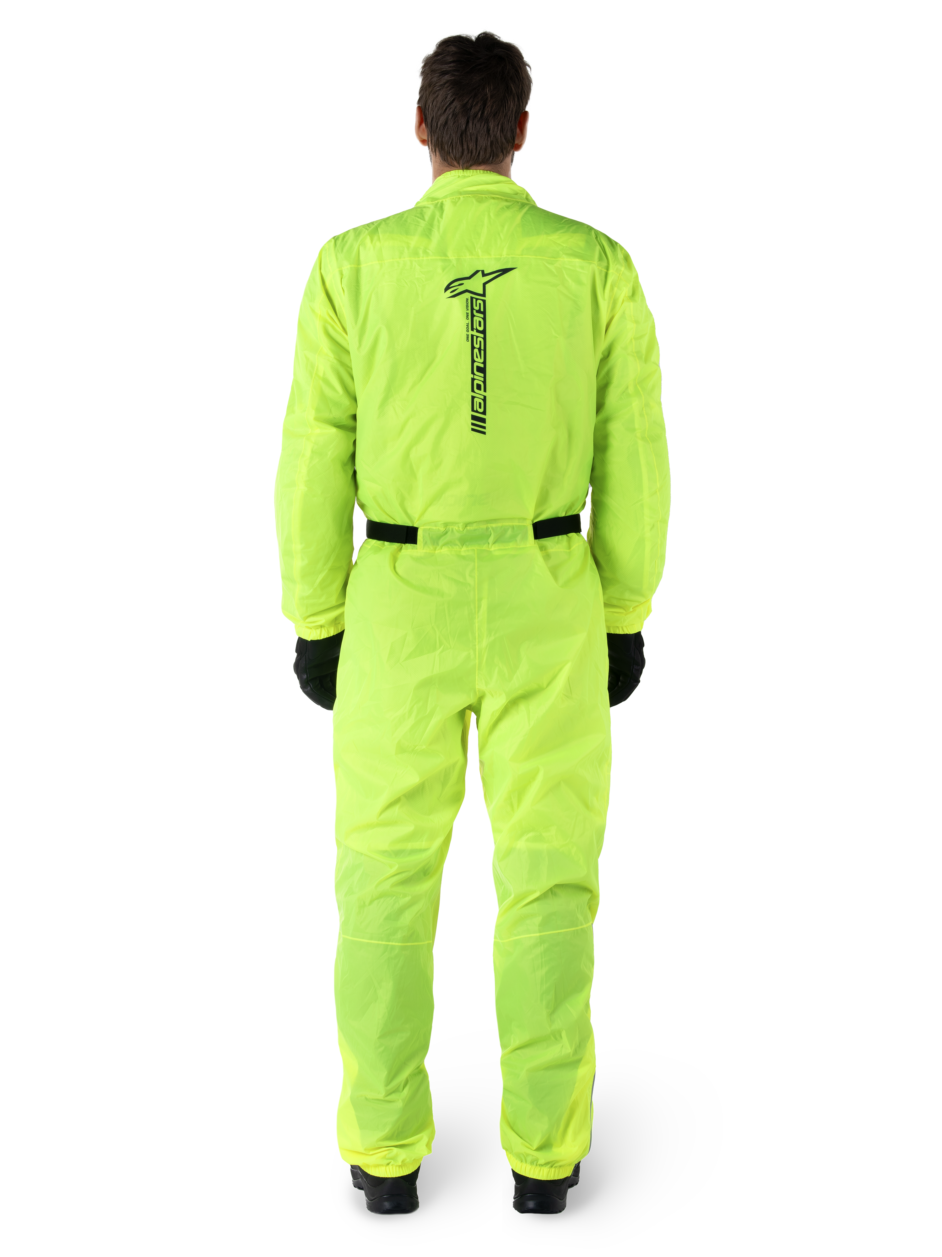 Tuta Alpinestars Hurricane Rain V2, tuta antipioggia da moto intera, giallo fluo, vista posteriore con marchio Alpinestars nero verticale, vita e polsini elasticizzati, indossata con guanti e stivali neri, abbigliamento tecnico impermeabile e antivento