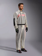 Alpinestars Kart Rain Suit, sovratuta da kart impermeabile trasparente, materiale semitrasparente che mostra una tuta da gara rosa e bianca sottostante, con cerniera asimmetrica nera, rinforzo sul gomito e fascia nera in vita, indossata con guanti da kart e scarpe da racing neri.