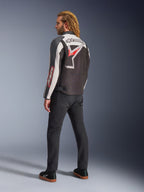Giacca Alpinestars Axton, giacca da moto, nero, bianco sporco e rosso acceso, vista posteriore indossata da un modello, con grande logo a stella Alpinestars e scritta sulla schiena, design d'ispirazione racing vintage con pannelli a fisarmonica, abbinata a pantaloni neri e sneakers