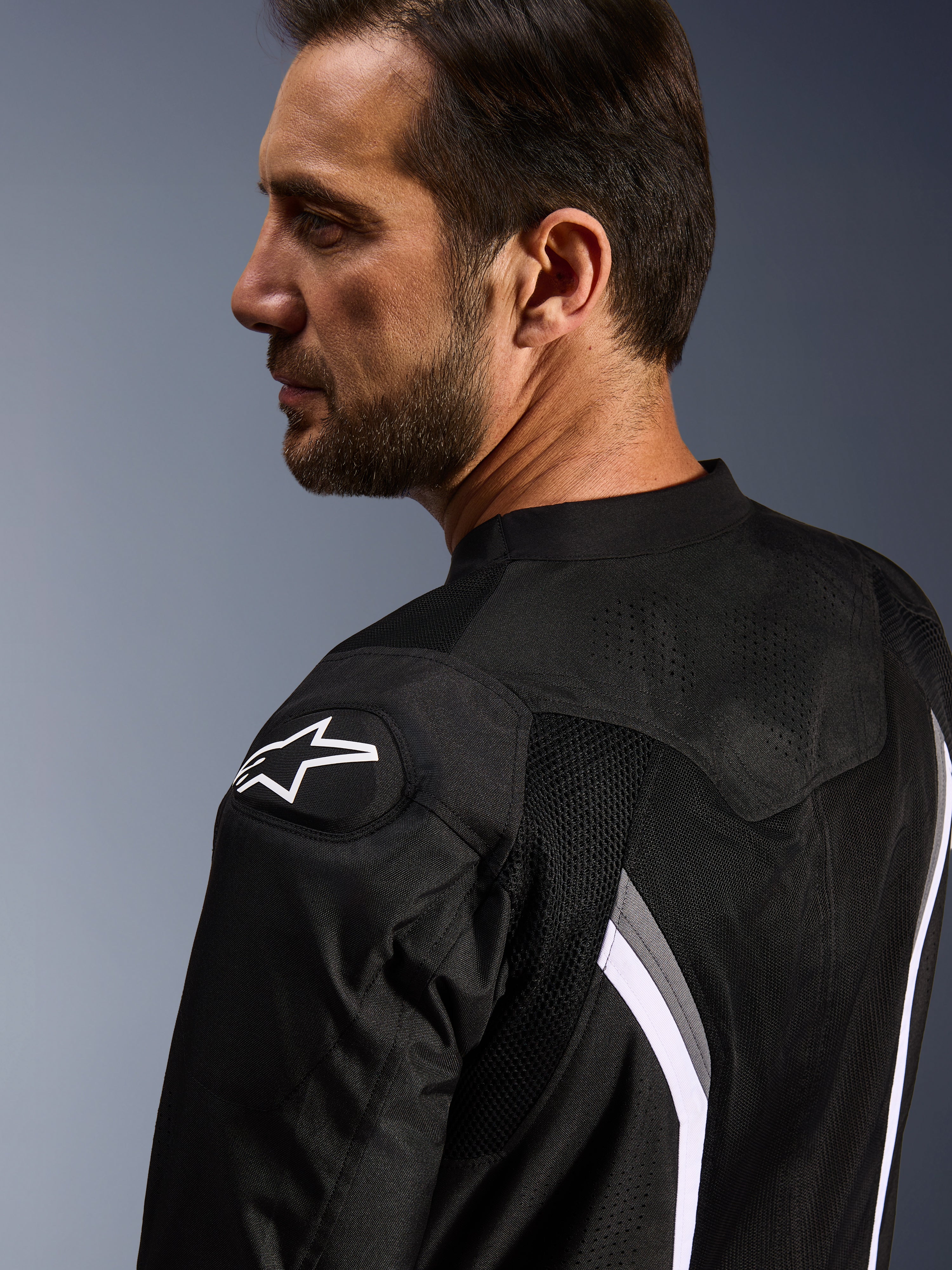 Alpinestars AST V3 Air Jacket, giacca da moto traforata, nero, grigio scuro e bianco, vista ravvicinata posteriore con logo a stella bianco sulla spalla e pannelli in mesh traforati al laser per la ventilazione.