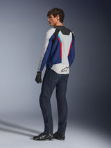 Alpinestars AST V3 Air Jacket, giacca da moto in argento, blu scuro e rosso brillante, vista posteriore indossata con jeans da moto blu scuro e attrezzatura nera, con pannelli in mesh traspirante e logo Alpinestars sul retro, abbigliamento tecnico da guida sport-fit.