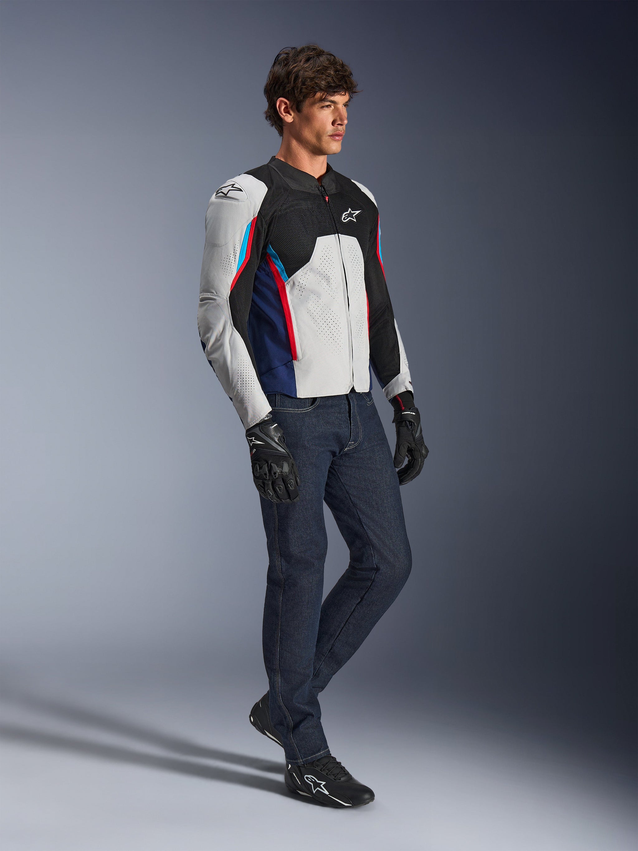 Giacca Alpinestars AST V3 Air, giacca da moto, argento, blu scuro e rosso acceso, indossata con jeans in denim scuro e guanti da guida neri, con pannelli in rete ventilata e design sport-fit per la guida in climi caldi
