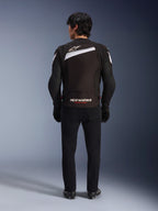 Giacca Alpinestars T-GP Plus R V4, giacca da moto sportiva in tessuto nero e bianco, vista posteriore con logo Alpinestars bianco e marchio 'RACING AHEAD', indossata con pantaloni e stivali neri, design aerodinamico per prestazioni elevate.