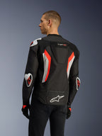 Giacca Alpinestars T-GP Air in nero e rosso fluo, vista posteriore a tre quarti su un modello, mette in risalto la gobba aerodinamica, le protezioni esterne Racing GP DFS su spalle e gomiti, i pannelli in mesh traforati al laser e i dettagli bianchi e rosso fluo, giacca da moto in tessuto dal taglio sportivo