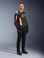 Giacca Alpinestars T-GP Air, Nero Rosso Fluo, indossata da un modello con pantaloni da moto e guanti neri, caratterizzata da pannelli in tessuto perforato al laser, logo Alpinestars bianco e accenti rossi, giacca da moto sportiva per la guida su strada in climi caldi