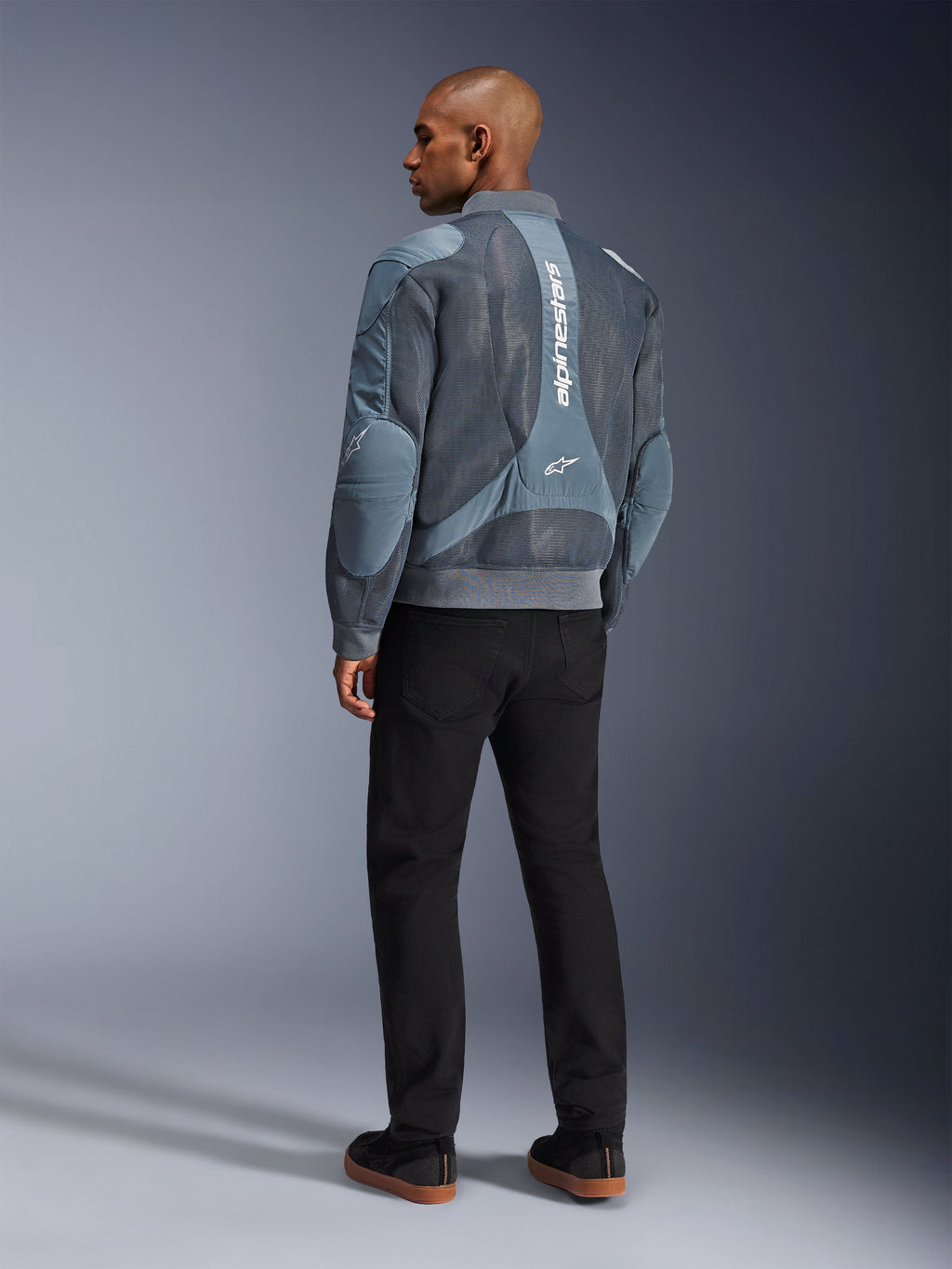 Alpinestars Flight Air Jacket, giacca da moto Storm Gray, vista posteriore, con pannelli di ventilazione in mesh 3D e marchio Alpinestars bianco verticale, indossata con pantaloni neri e sneakers nere, stile urban commuter