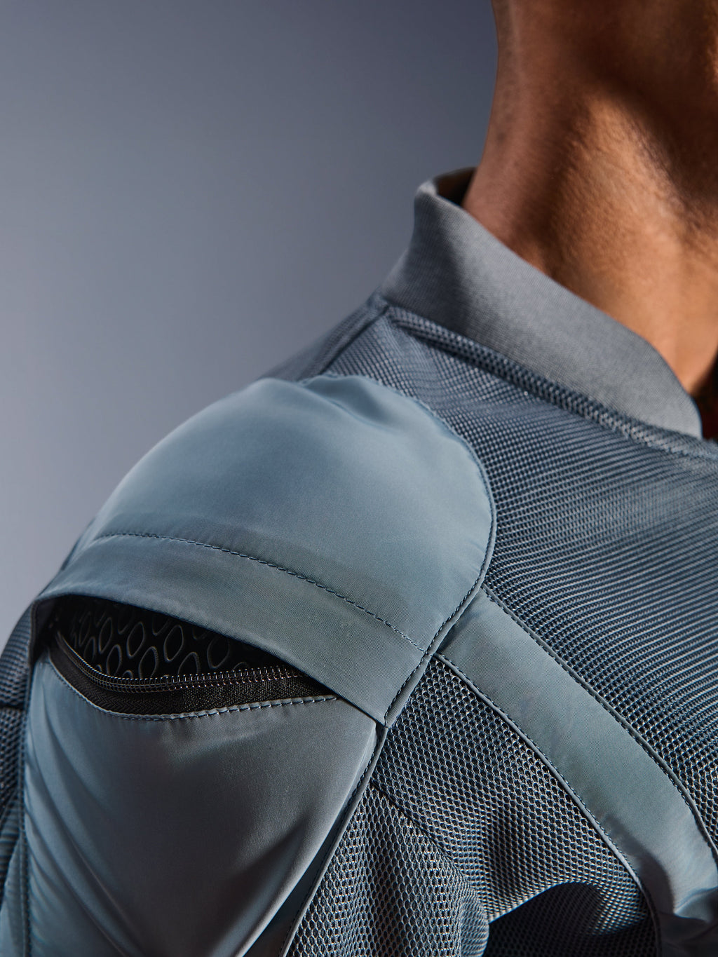 Primo piano della giacca Alpinestars Flight Air in Storm Gray, che mette in risalto la tasca esterna per la protezione della spalla con armatura a nido d'ape visibile, i pannelli di ventilazione in mesh 3D e il colletto a costine per la guida motociclistica urbana tecnica
