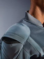 Primo piano della giacca Alpinestars Flight Air in Storm Gray, che mette in risalto la tasca esterna per la protezione della spalla con armatura a nido d'ape visibile, i pannelli di ventilazione in mesh 3D e il colletto a costine per la guida motociclistica urbana tecnica