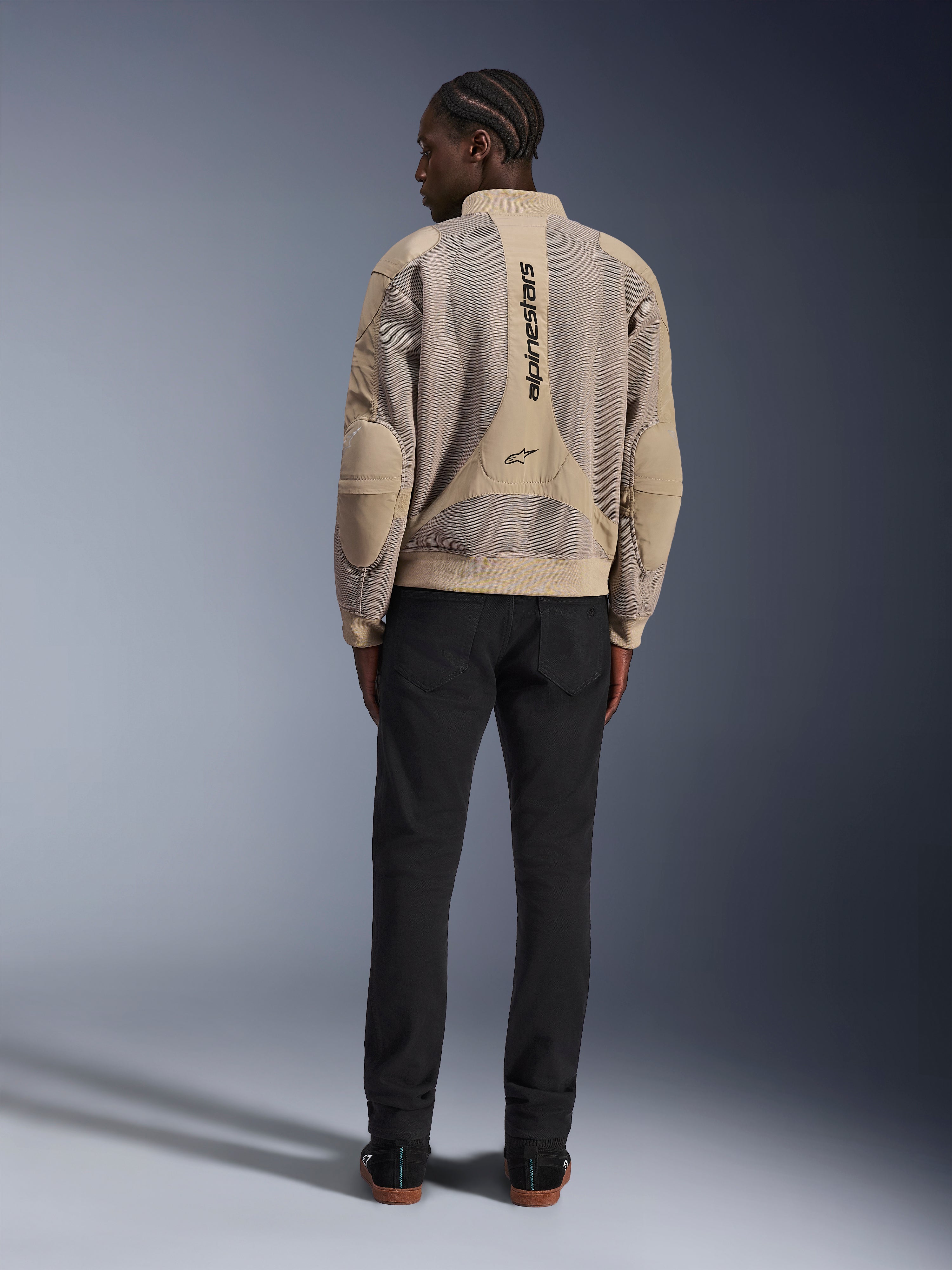 Giacca Alpinestars Flight Air, giacca da moto urbana color sabbia, vista posteriore con pannelli traspiranti in mesh 3D e logo verticale, indossata con pantaloni neri per un look moderno in stile street-style