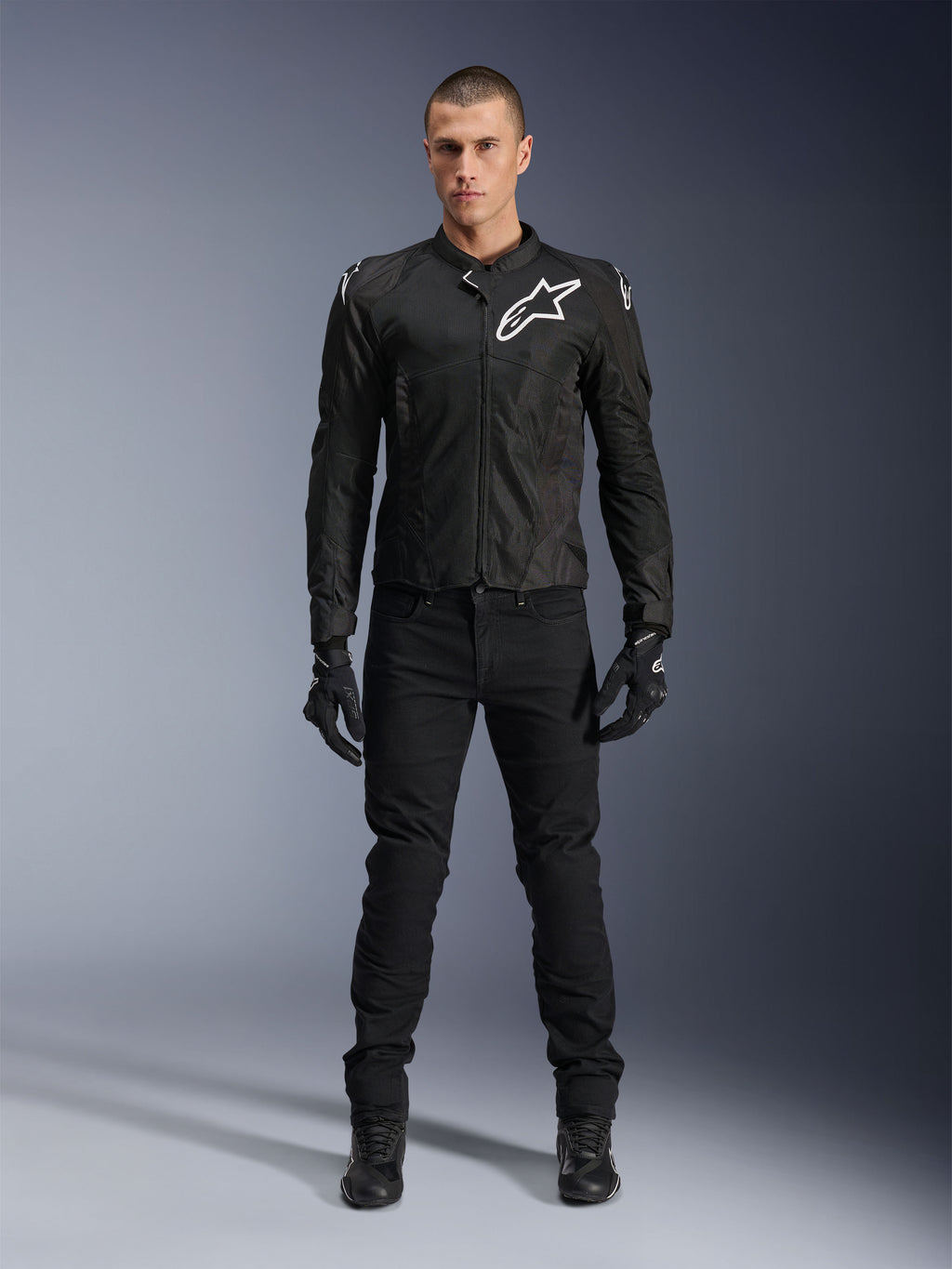 Giacca Alpinestars Viper Air V4, giacca da moto in tessuto nero, logo bianco su petto e spalle, indossata con pantaloni e guanti da moto neri, dotata di pannelli in rete tecnica per la ventilazione, vista in studio a figura intera