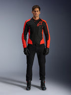 Modello che indossa la giacca Alpinestars Viper Air V4 in rosso fluo e nero, abbinata a pantaloni da moto, guanti e stivali neri, con pannelli in mesh traspirante per la ventilazione e un audace logo a stella sul petto, abbigliamento sportivo da moto da strada