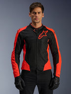 Giacca Alpinestars Viper Air V4, giacca da moto racing, rosso fluo e nero, indossata da un modello con guanti neri, pannelli in mesh tecnico per la ventilazione, design sportivo con logo Alpinestars a stella sul petto
