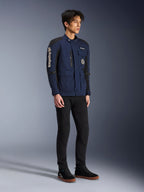 Giacca Alpinestars Dice, blu scuro e nero, moderna giacca da moto in stile field indossata da un modello con pantaloni neri e sneakers alte nere, dotata di molteplici tasche utility, marchio Alpinestars verticale sulla manica e toppe in tessuto, abbigliamento tecnico urbano contemporaneo