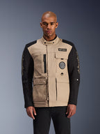 Alpinestars Dice Jacket, giacca moto urbana, beige e nero, estetica workwear robusta con tasche utility multiple e patch sul petto, colletto alto con chiusura a bottone, branding vistoso sulle maniche, indossata da un modello