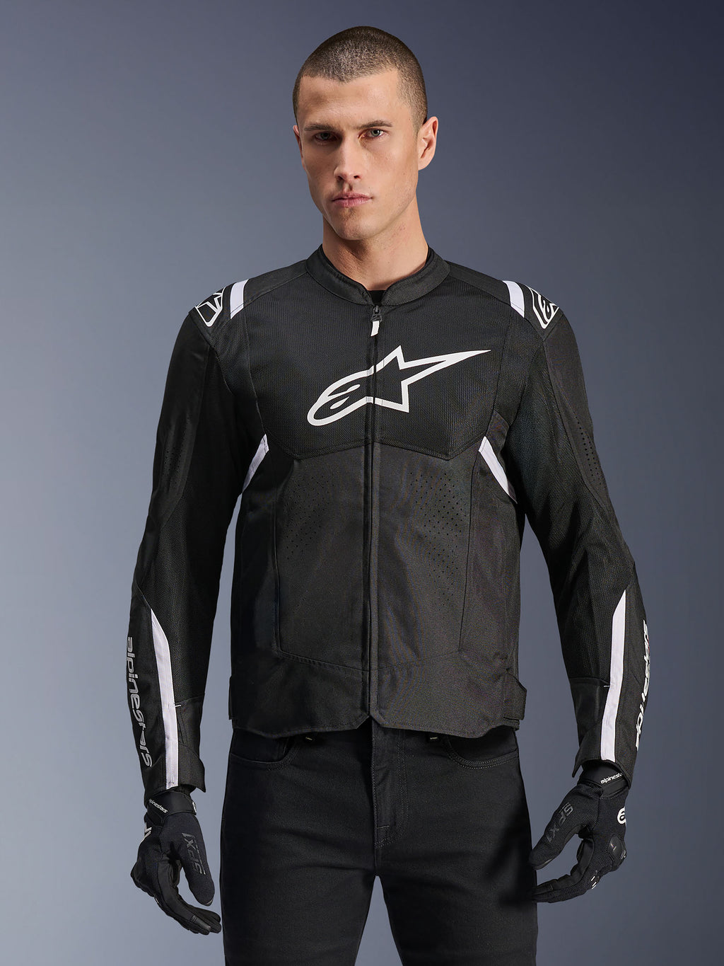 Alpinestars Giacca T-SPS Air V2, giacca da moto in tessuto, nera con dettagli bianchi, grande logo bianco sul petto, design in mesh traforato per la ventilazione, indossata con pantaloni e guanti neri