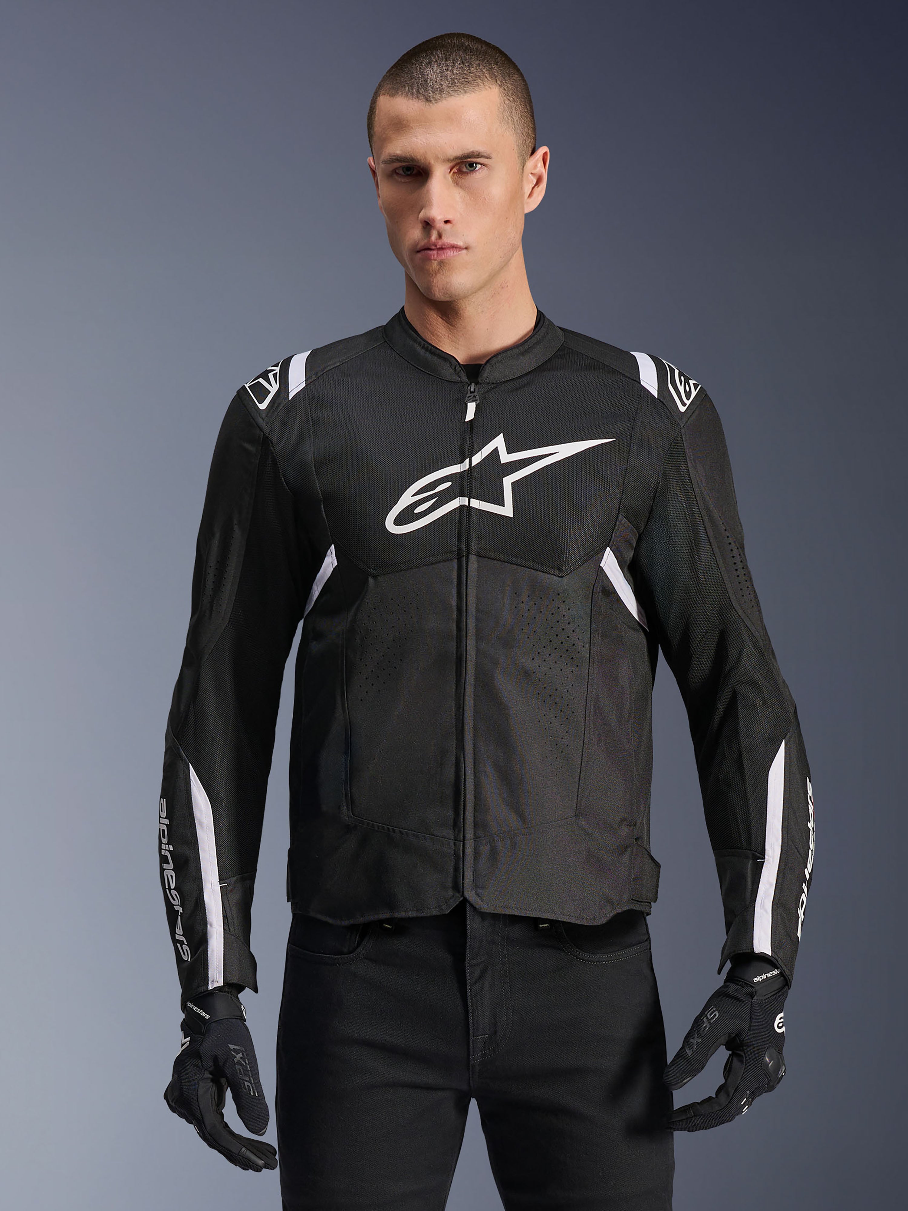 Alpinestars Giacca T-SPS Air V2, giacca da moto in tessuto, nera con dettagli bianchi, grande logo bianco sul petto, design in mesh traforato per la ventilazione, indossata con pantaloni e guanti neri