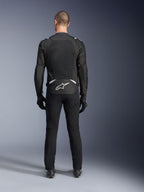 Giacca Alpinestars T-Sps Air V2, vista posteriore, giacca da moto in tessuto nero e bianco, dotata di un ampio pannello posteriore in mesh per il massimo flusso d'aria e logo Astars bianco sulla parte bassa della schiena, indossata con pantaloni e guanti da moto neri