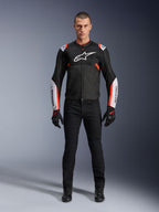 Modello che indossa la giacca Alpinestars T-Sps Air V2 in Black White Red Fluo, caratterizzata da ampi pannelli in mesh tecnico e logo bianco su petto e maniche, abbinata a pantaloni tecnici da guida e guanti neri, abbigliamento da moto sportivo urbano