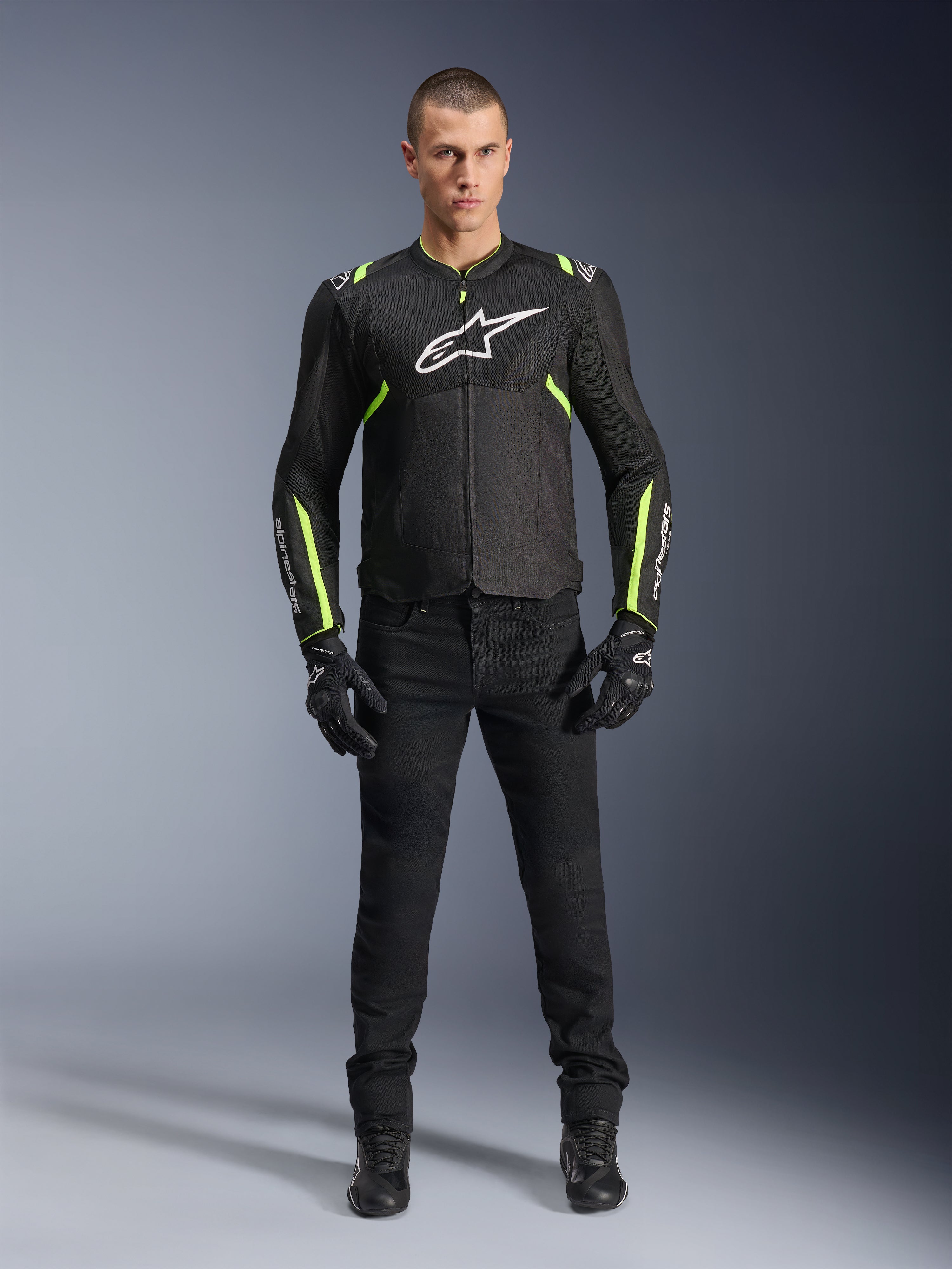 Giacca Alpinestars T-Sps Air V2, nero e giallo fluo, giacca da moto in tessuto con pannelli in rete, indossata da un modello uomo con pantaloni e guanti neri, con logo Alpinestars bianco sul petto, abbigliamento da moto urban sport