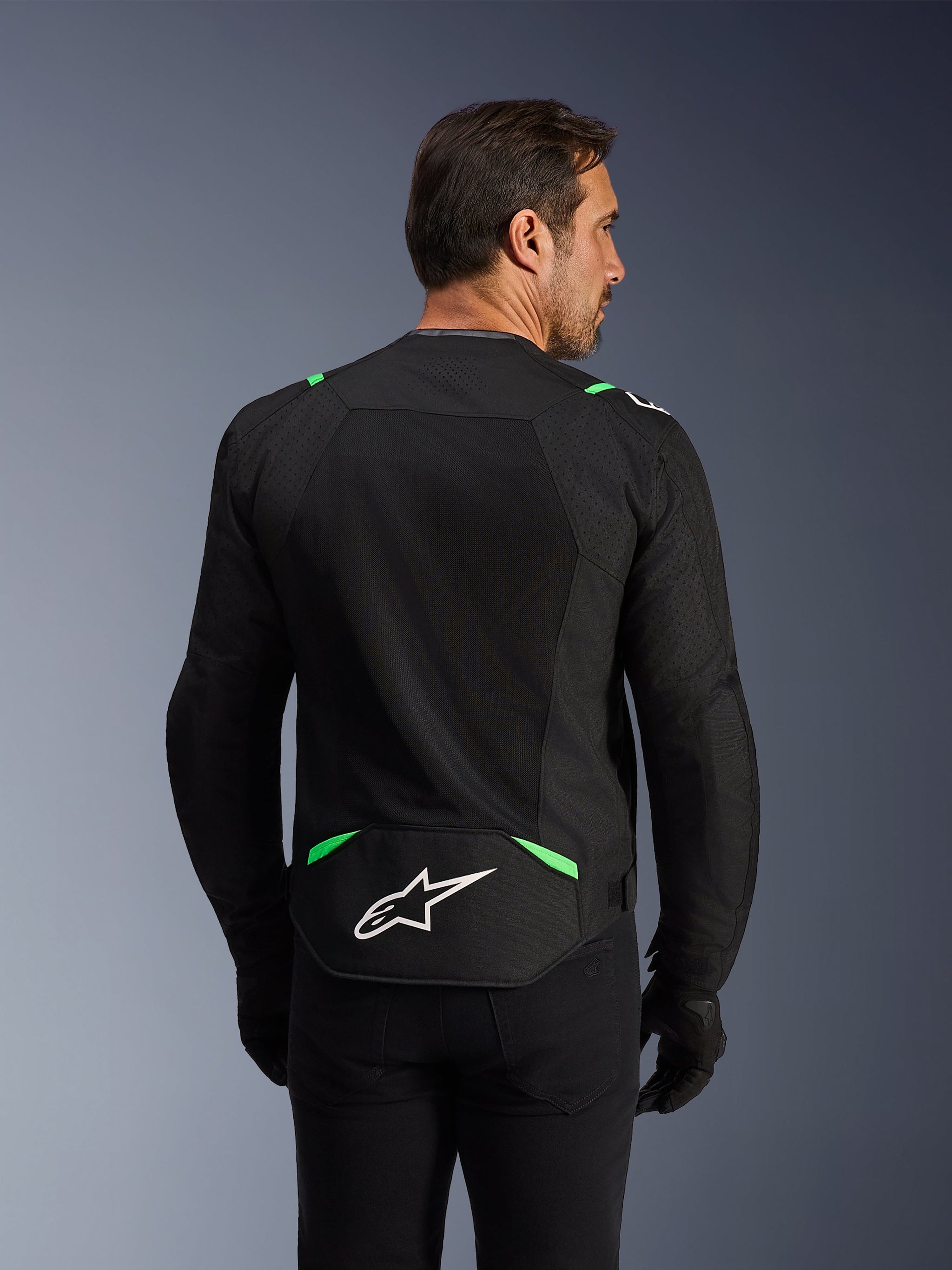 Giacca Alpinestars T-SPS Air V2, giacca da moto in tessuto, nero e verde fluo, vista posteriore con ampi pannelli in rete tecnica per la ventilazione, logo Alpinestars bianco sulla parte bassa della schiena, vestibilità ergonomica dal taglio sportivo per la guida urbana