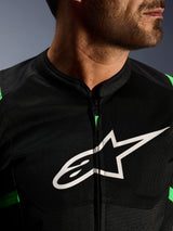 Primo piano della giacca Alpinestars T-SPS Air V2, nero e verde fluo, con pannelli in rete tecnica traspirante, cerniera centrale e prominente logo a stella Alpinestars bianco sul petto, abbigliamento tecnico da moto