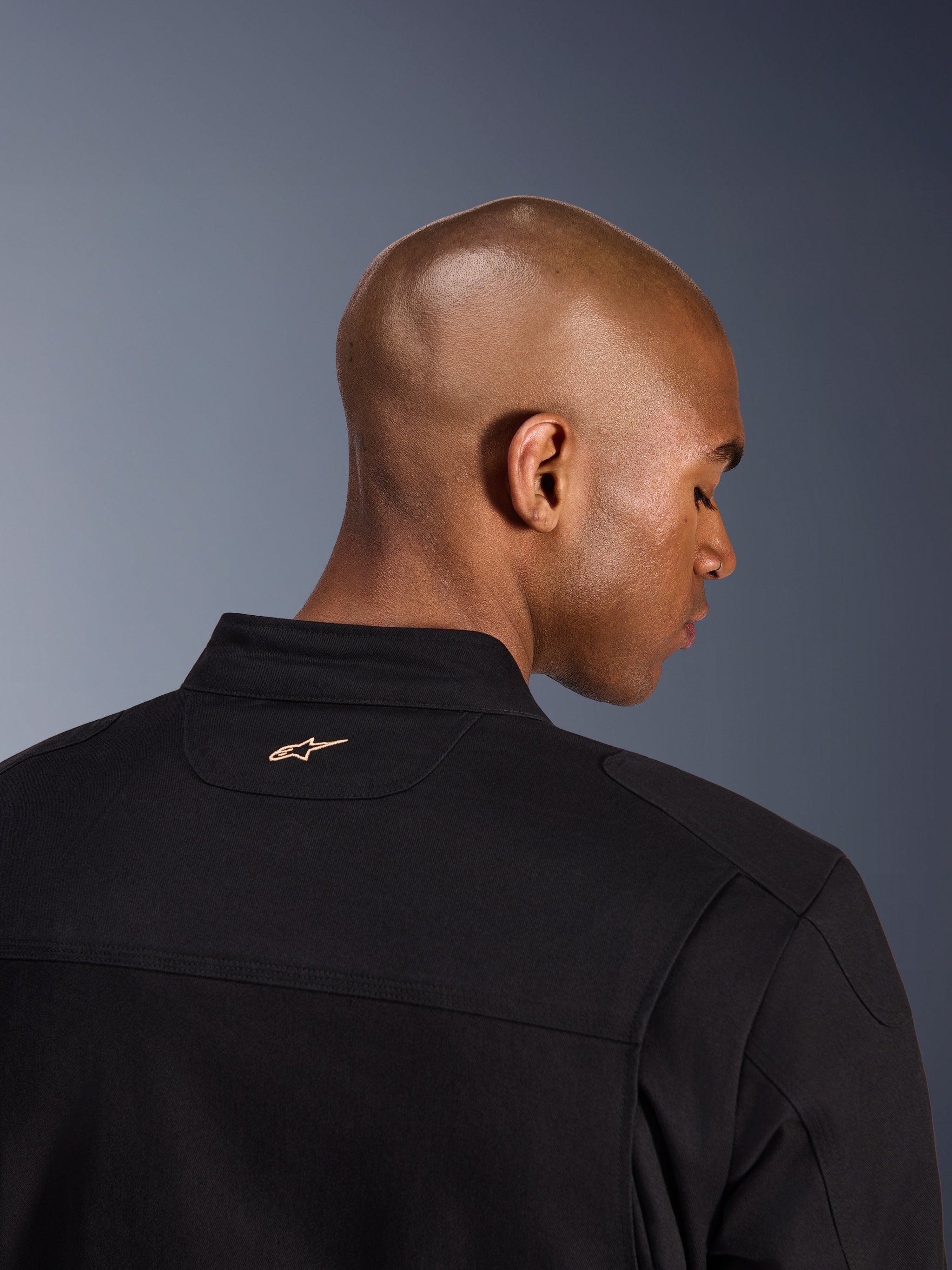 Alpinestars Giacca Bruiser, nero, dettaglio posteriore del colletto e della parte superiore delle spalle, con piccolo logo Alpinestars ricamato color tan sul collo, giacca da moto urbana con estetica workwear