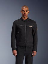 Giacca Alpinestars Bruiser, giacca da moto urbana nera, vista frontale su un modello, con estetica workwear classica, tasche sul petto con cerniera, colletto con bottone e logo Alpinestars, progettata per i motociclisti urbani