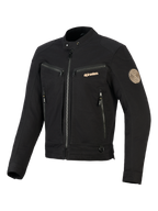 Giacca Alpinestars Bruiser, giacca da moto urbana nera, dotata di tasche con zip sul petto e per le mani, branding color oro e patch Oscar a spirale sulla spalla, design tessile ispirato al workwear.