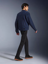 Giacca Alpinestars Bruiser in Dark Blue, giacca da moto urbana in tessuto, vista posteriore su modello che cammina, abbinata a pantaloni neri e sneakers con suola in gomma, con design ispirato al workwear e regolazioni in vita.