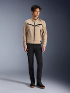 Giacca Alpinestars Bruiser, giacca da moto urbana color Aluminum, indossata con pantaloni neri e sneaker nere, caratterizzata da tasche nere con zip e colletto con bottone a pressione, design contemporaneo ispirato al workwear per la guida urbana