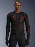 Giacca Alpinestars Troop-Air Pro, giacca da moto tecnica in rete corazzata in nero e rosso fluo, indossata da un modello, caratterizzata da ampi pannelli di ventilazione in rete, base rossa e tiranti delle cerniere rossi, stile urban riding.
