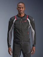 Alpinestars Troop-Air Pro Jacket, nero, grigio cenere e rosso brillante, indossata da un modello, giacca da moto in mesh con pannelli di ventilazione traforati, con tasche con cerniera rosse e loghi bianchi sulle spalle, abbigliamento tecnico protettivo