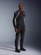 Giacca Alpinestars Troop-Air Pro, nero grigio cenere e rosso brillante, giacca tecnica a rete corazzata, con accenti rossi e logo bianco sulla spalla, indossata con pantaloni e stivali neri coordinati, abbigliamento da moto urbano moderno