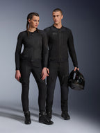 Alpinestars Stella Troop-Air Jacket, uomo e donna con abbigliamento tecnico da moto coordinato tutto nero, caratterizzato da struttura in mesh per la ventilazione, pantaloni e stivali neri, uomo con casco nero, abbigliamento per guida urbana.