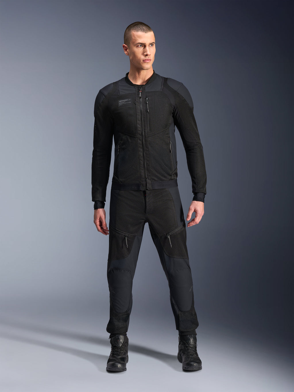 Giacca Alpinestars Troop-Air Pro, giacca tecnica da moto corazzata nera, caratterizzata da pannelli in mesh e cerniere frontali, indossata con pantaloni neri coordinati e stivali da guida, abbigliamento stradale urbano premium
