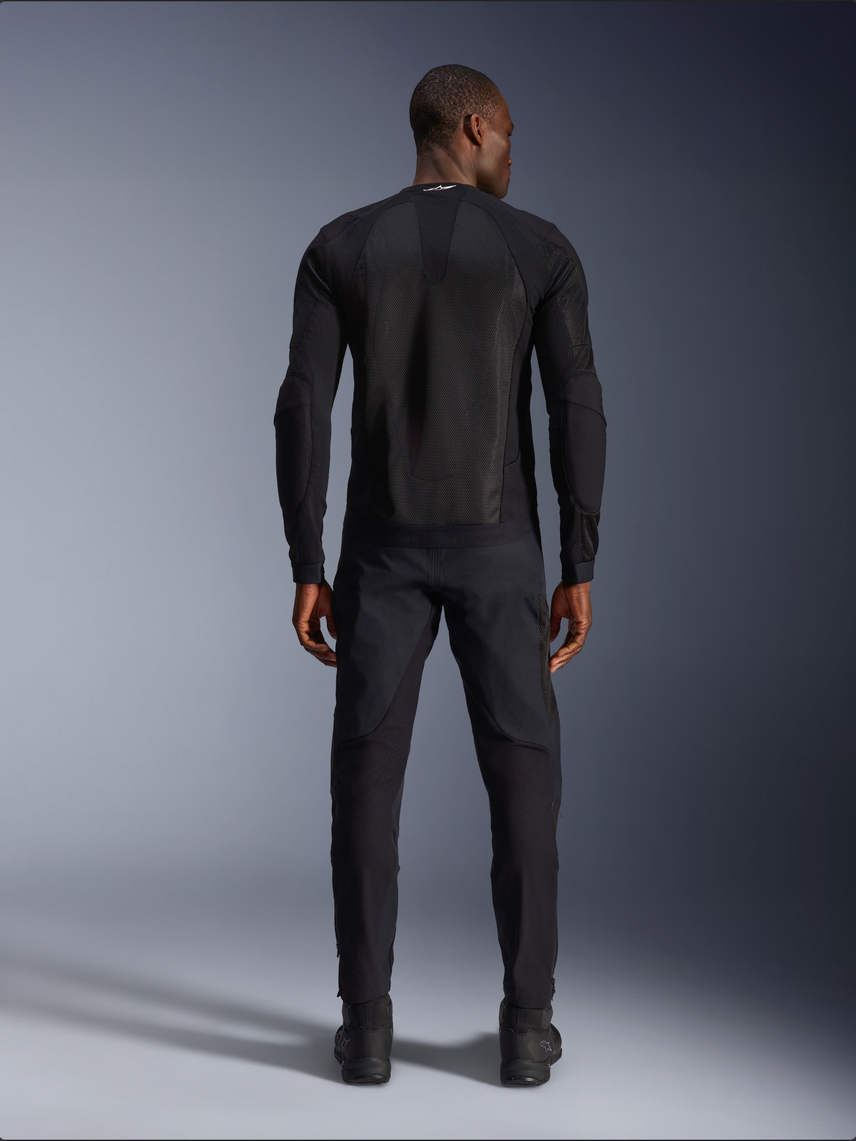 Giacca Alpinestars Troop-Air in Black Black, vista posteriore con pannello posteriore in mesh tecnica e costruzione ventilata, abbinata a pantaloni e stivali da moto neri coordinati