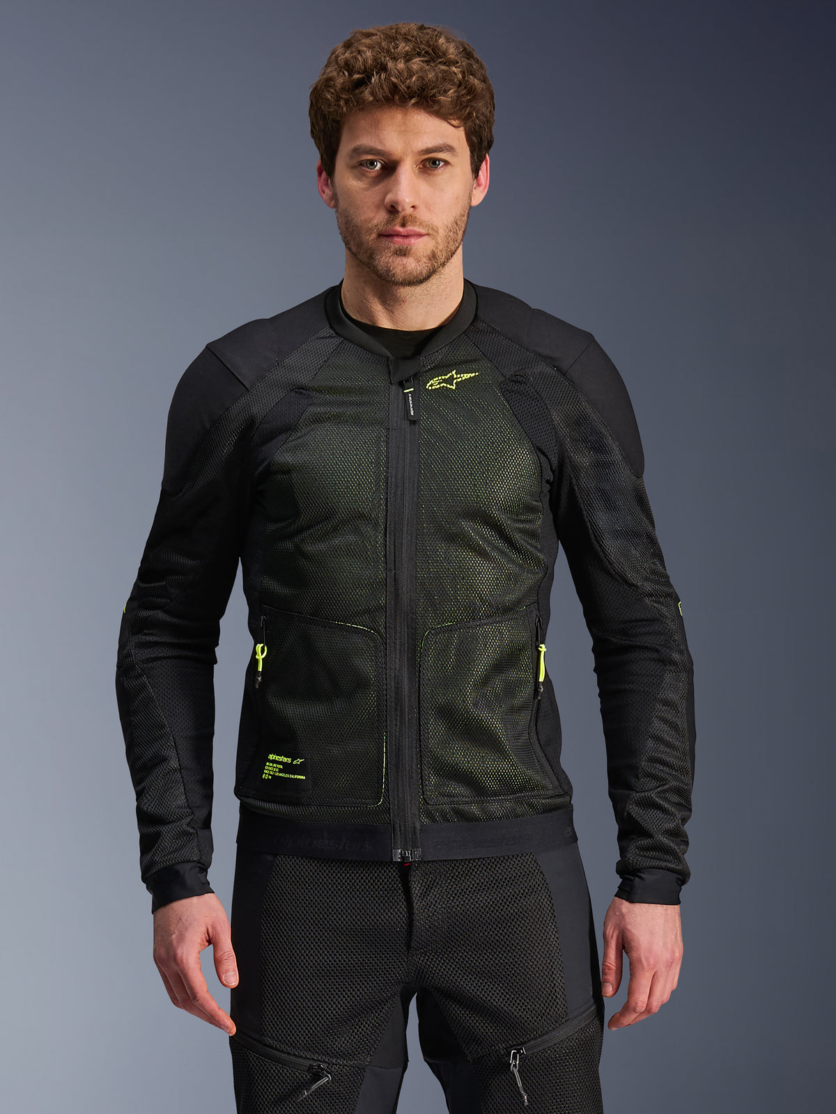 Alpinestars Troop-Air Jacket, giacca tecnica da moto per guida urbana, nero e giallo fluo, indossata da un modello, con struttura in mesh leggero, cerniere e loghi giallo neon
