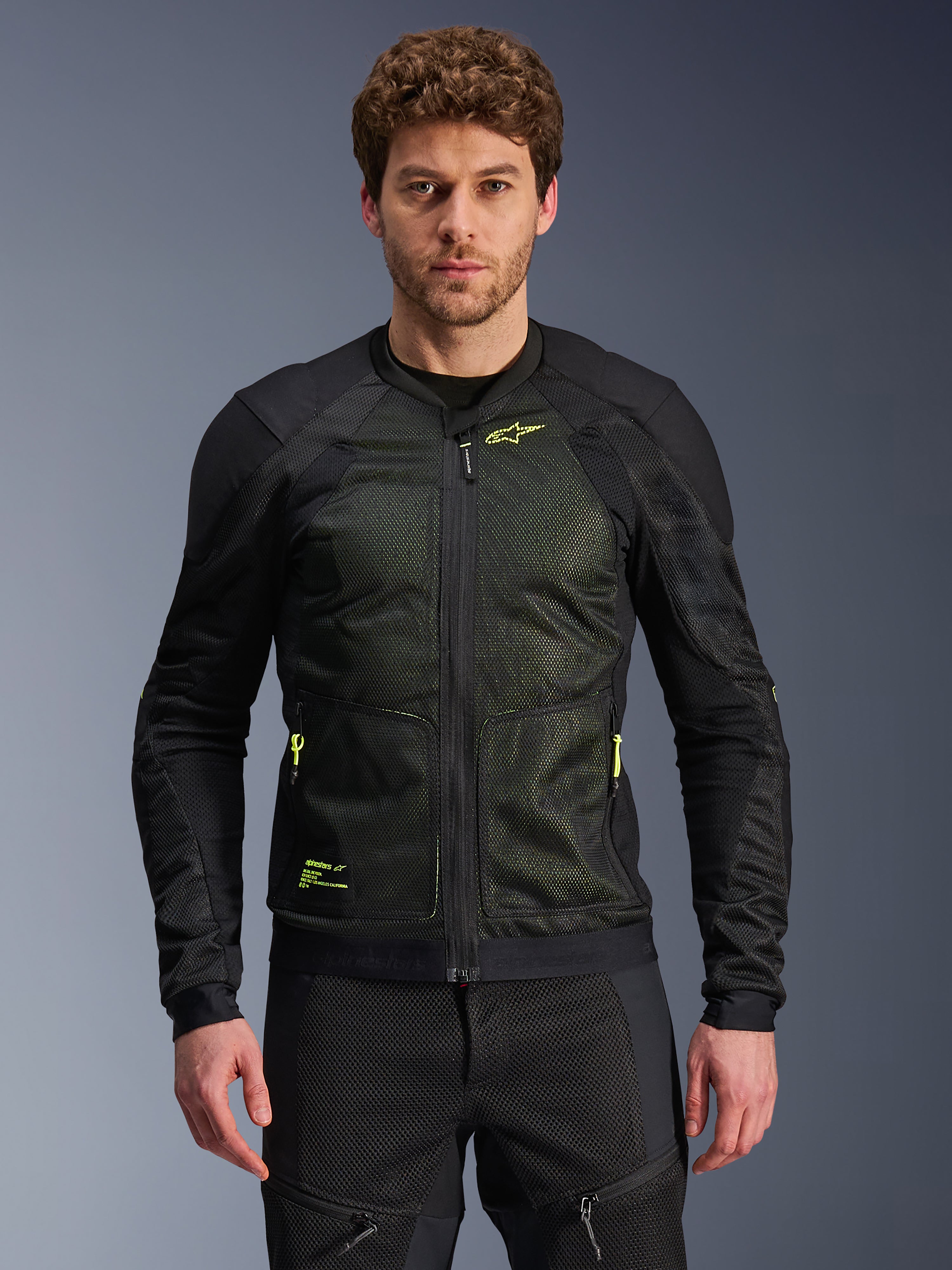 Alpinestars Troop-Air Jacket, giacca tecnica da moto per guida urbana, nero e giallo fluo, indossata da un modello, con struttura in mesh leggero, cerniere e loghi giallo neon