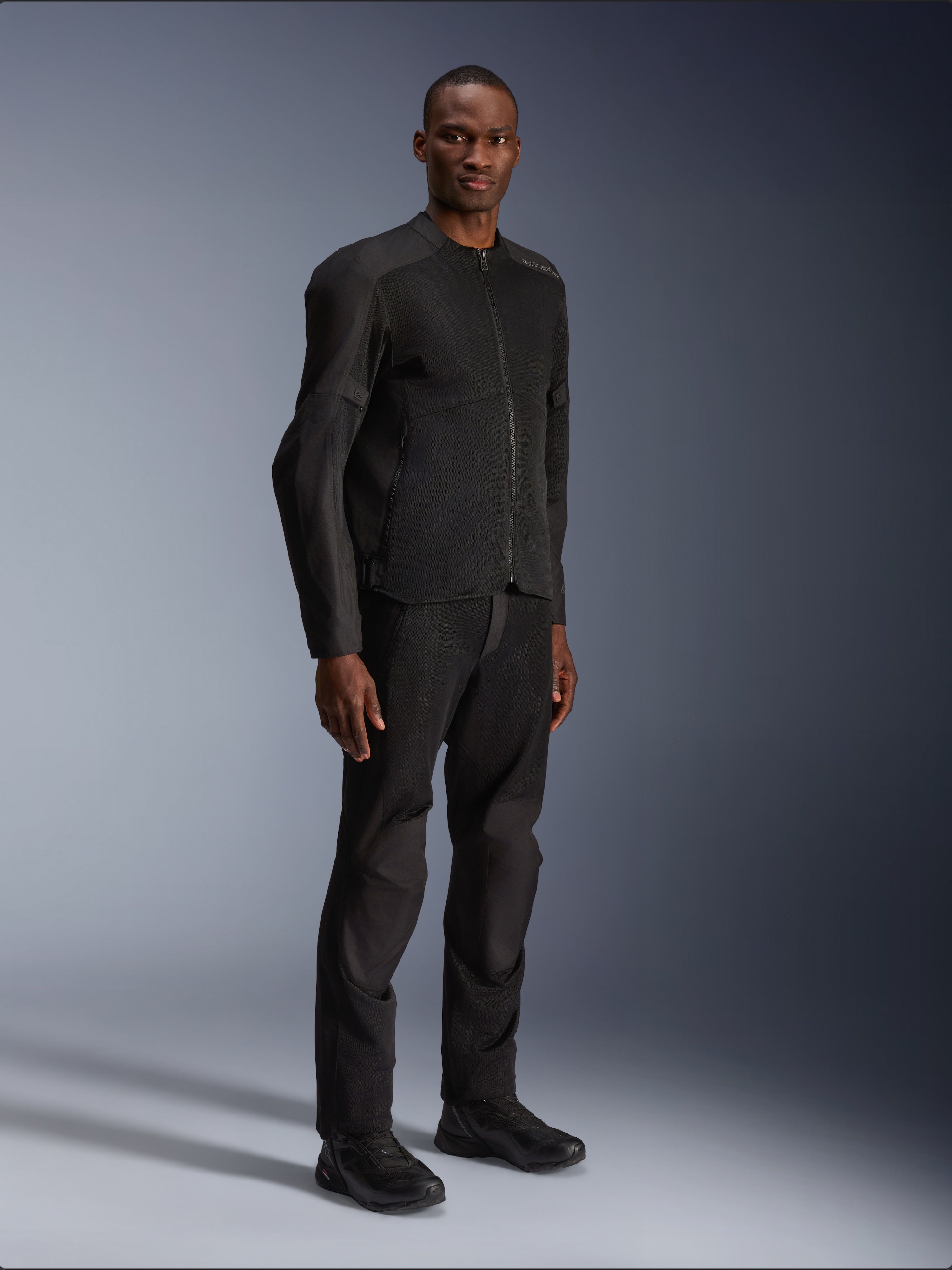 Giacca Alpinestars C-1 Air, nero, indossata da un modello con pantaloni e scarpe da moto neri coordinati, con ampi pannelli in rete tecnica per il flusso d'aria, estetica urban pulita e vestibilità lineare.