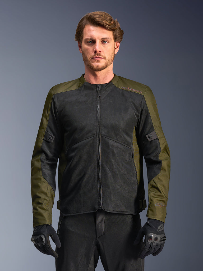 Giacca Alpinestars C-1 Air, Khaki e nero, giacca da moto da uomo con ampi pannelli in rete tecnica per il massimo flusso d'aria, indossata da un modello con pantaloni e guanti da moto neri, design urban contemporary per il pendolarismo.