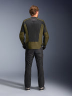 Vista posteriore di un motociclista che indossa la giacca Alpinestars C-1 Air in kaki e nero, con un ampio pannello posteriore in rete tecnica per la ventilazione, abbinata a pantaloni da moto neri, abbigliamento urban contemporary per guida su strada.