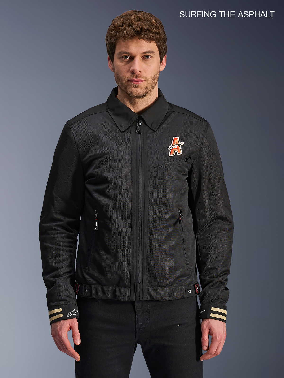 Alpinestars Giacca Ignite Air, giacca da moto urbana da uomo in nero, vista anteriore indossata da un modello con colletto tradizionale a camicia, grafiche sul petto ispirate al club e struttura certificata CE