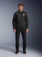 Alpinestars Ignite Air Jacket, giacca da moto nera con colletto a camicia, cerniera frontale e logo arancione sul petto, indossata da un modello con pantaloni e sneakers nere per un look urban contemporary.