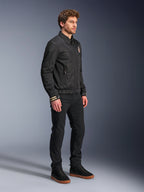 Giacca Alpinestars Ignite Air, giacca da moto urbana, nera, indossata da un modello con pantaloni neri e sneakers nere, con colletto a camicia tradizionale, grafiche ispirate al club su petto e polsini, design contemporaneo ed elegante con finitura in rete e raso