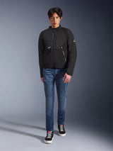 Modello maschile che indossa la giacca Alpinestars Provoke in nero, giacca da moto urbana in tessuto con cerniere tecniche e pannelli in softshell ripstop, abbinata a jeans blu e sneakers nere, stile urban rider contemporaneo.
