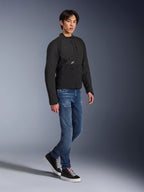 Giacca Alpinestars Provoke, giacca da moto urbana, nero, indossata da un modello con jeans blu e sneakers nere, design tecnico in tessuto con piccolo logo Alpinestars, scatto lifestyle a figura intera per la guida urbana contemporanea