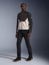 Modello che indossa la giacca Alpinestars Provoke in Black Metal Gray, caratterizzata da distintive cerniere rosse frontali e sulle tasche, abbinata a pantaloni neri e sneakers alte nere con suola color para, abbigliamento da moto urban contemporary per un look street-ready.